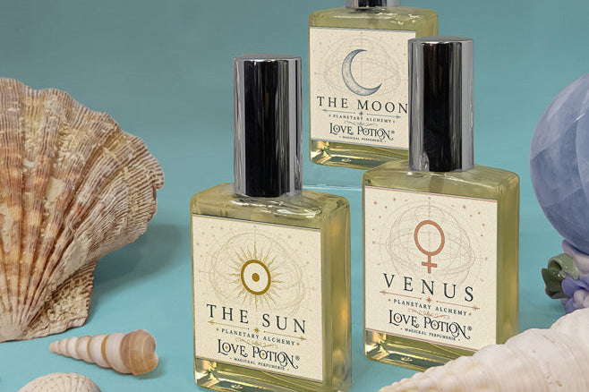 Summer-scented new perfumes by Love Potion with a teal background, blue crystal, and various seashells.