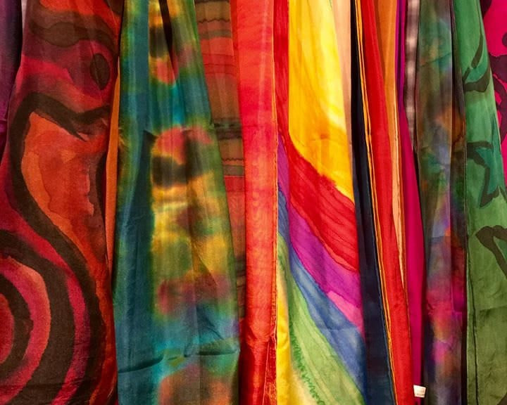 Colorful tie-dye fabrics hanging on a rack.