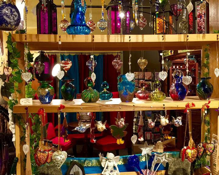 Display of various decorative items including hanging ornaments and fairy garden houses on a wooden shelf.