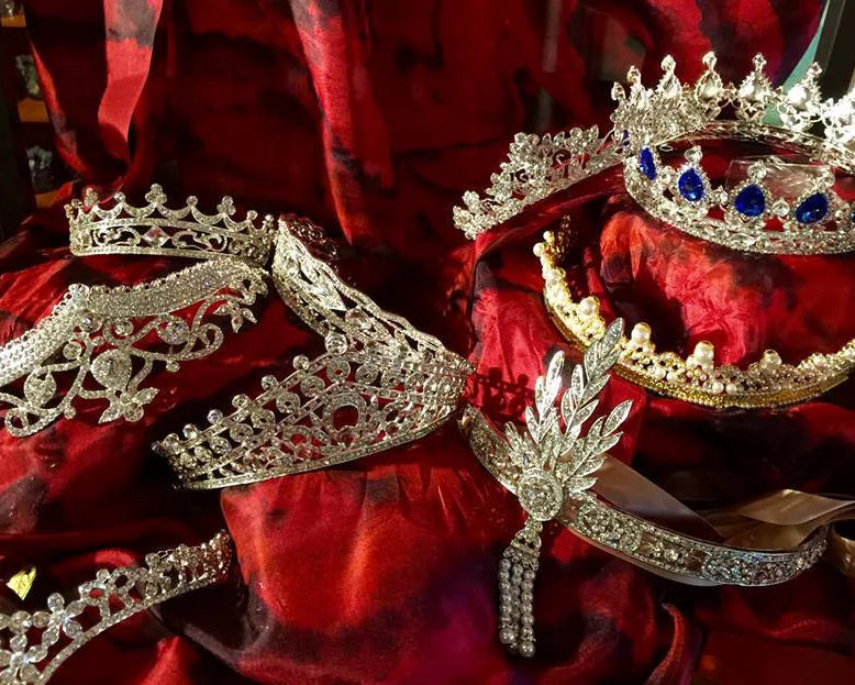 Set of decorative jeweled tiaras on a red fabric background.