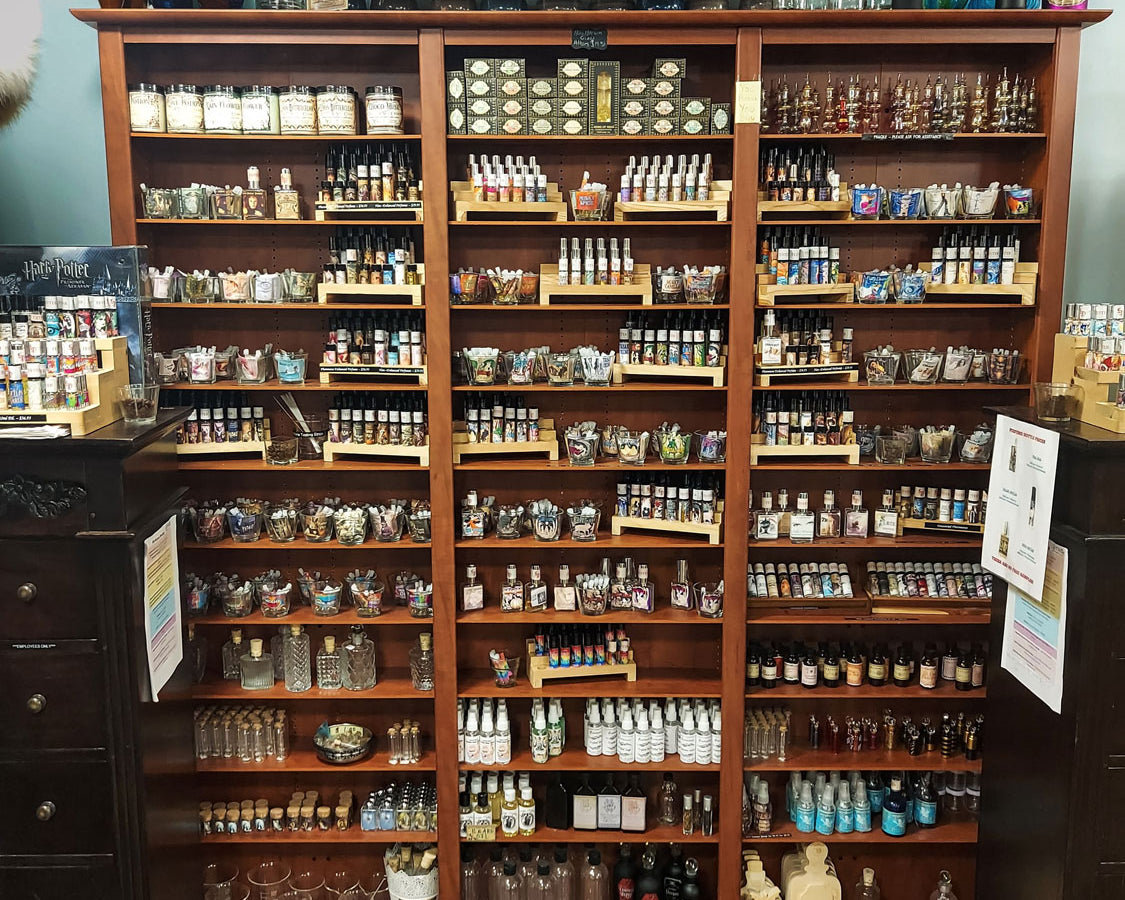 Full-wall shelf displaying various bottles of Love Potion Perfumes with a decorative sign above.