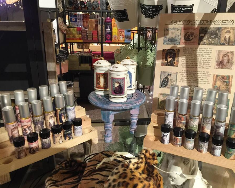 Valentine perfume display with sample roller bottles, vintage cat painting spice jars, and leopard & tiger print pouches.