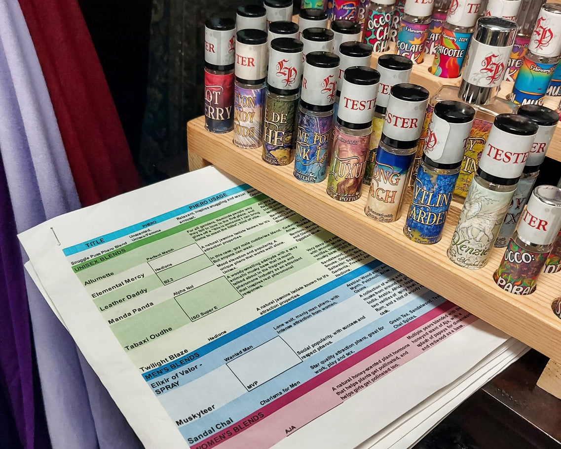 Collection of perfume tester roller bottles on a wooden shelf with a perfume & pheromone info cheat sheet.