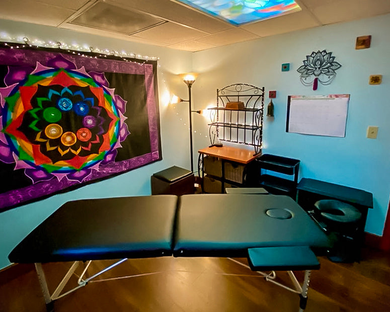The massage table and display shelf areas in our Room of Requirement, with fairy lights and a chakra tapestry on the wall.