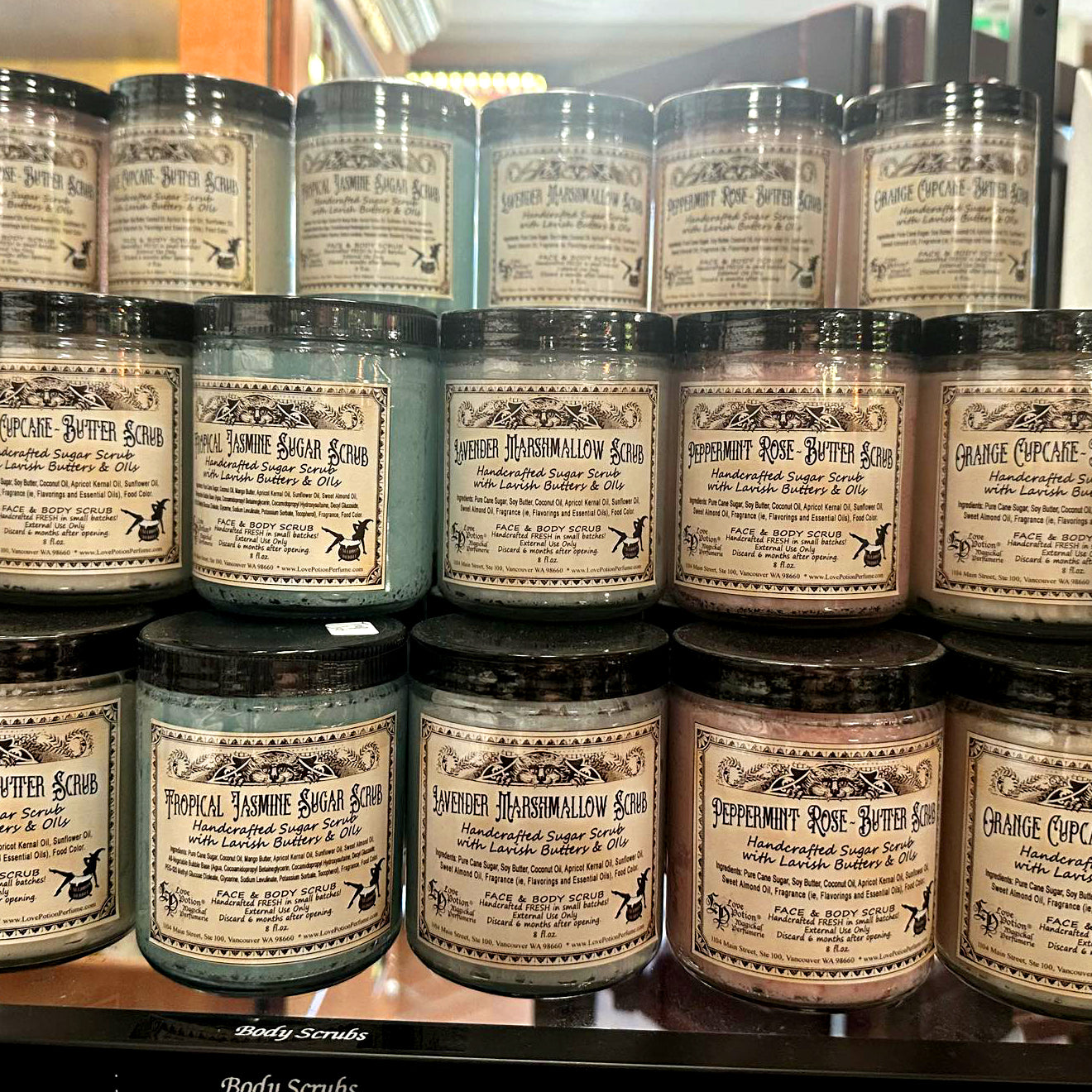 Jars of handmade sugar and butter scrubs stacked in the Love Potion Magickal Marketplace