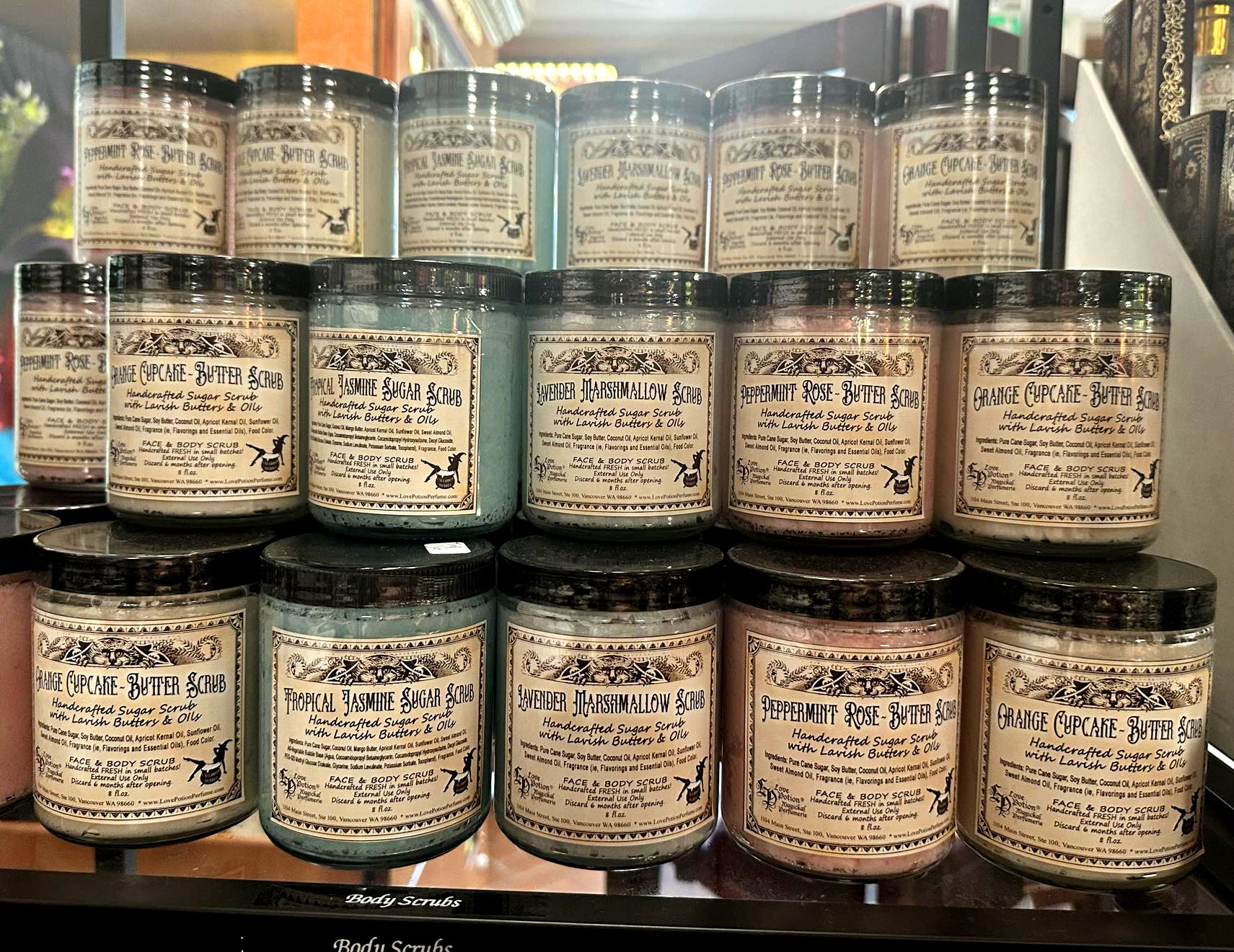 Jars of handmade sugar and butter scrubs stacked in the Love Potion Magickal Marketplace