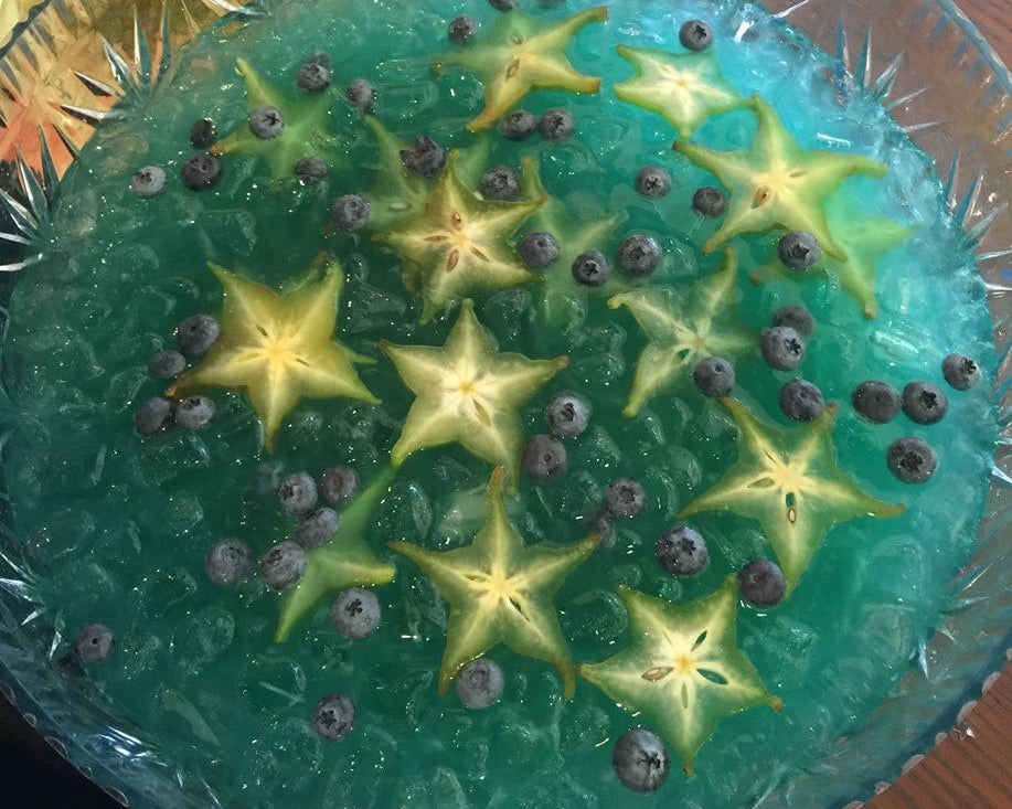 Punch bowl filled with star fruit slices and blueberries in a blue fruit punch for one of our shop parties.