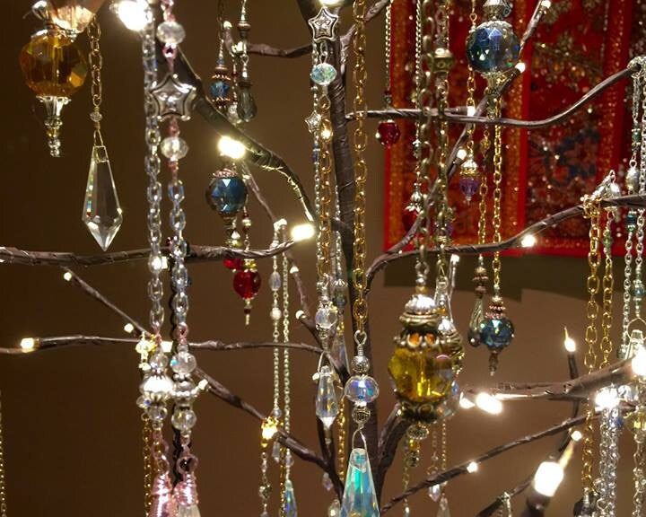 Crystal pendant ornaments and sun catchers hanging on the limbs of an artificial tree with fairy lights.