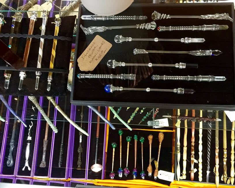 Collection of decorative wood, resin, metal, and crystal wands in a display case at our store.