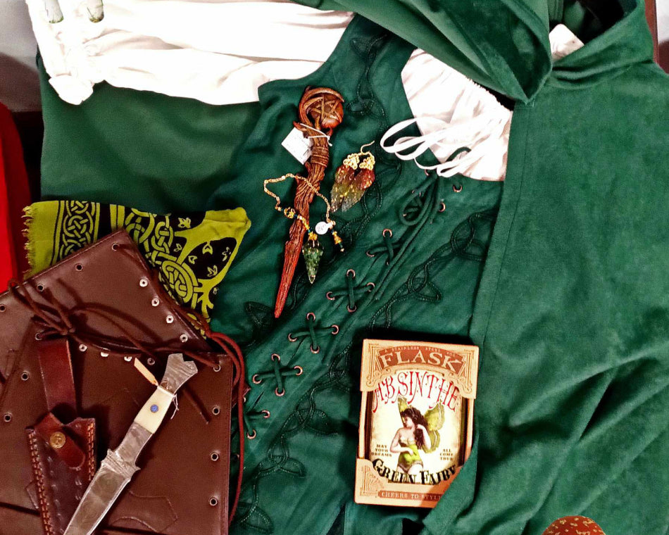Green Celtic dress, cloak, wooden wand, mushroom stickers, fairy flask, bone dagger, pendulum, and fairy wing earrings.
