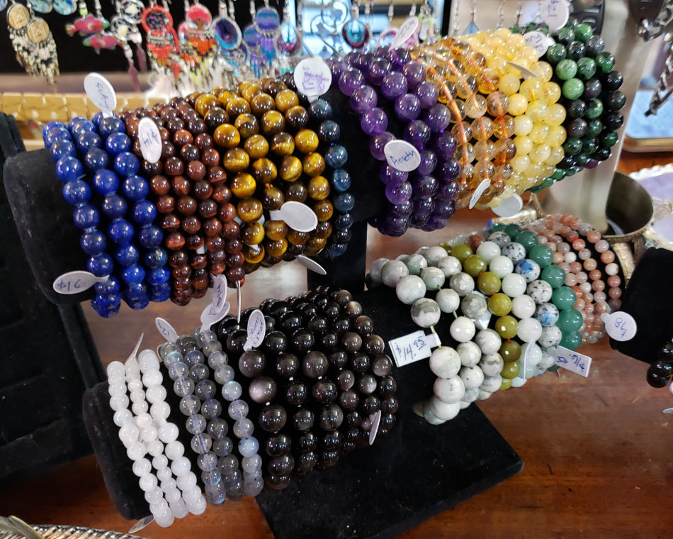 Assortment of large crystal bracelets on a black velvet jewelry display at Love Potion Marketplace.