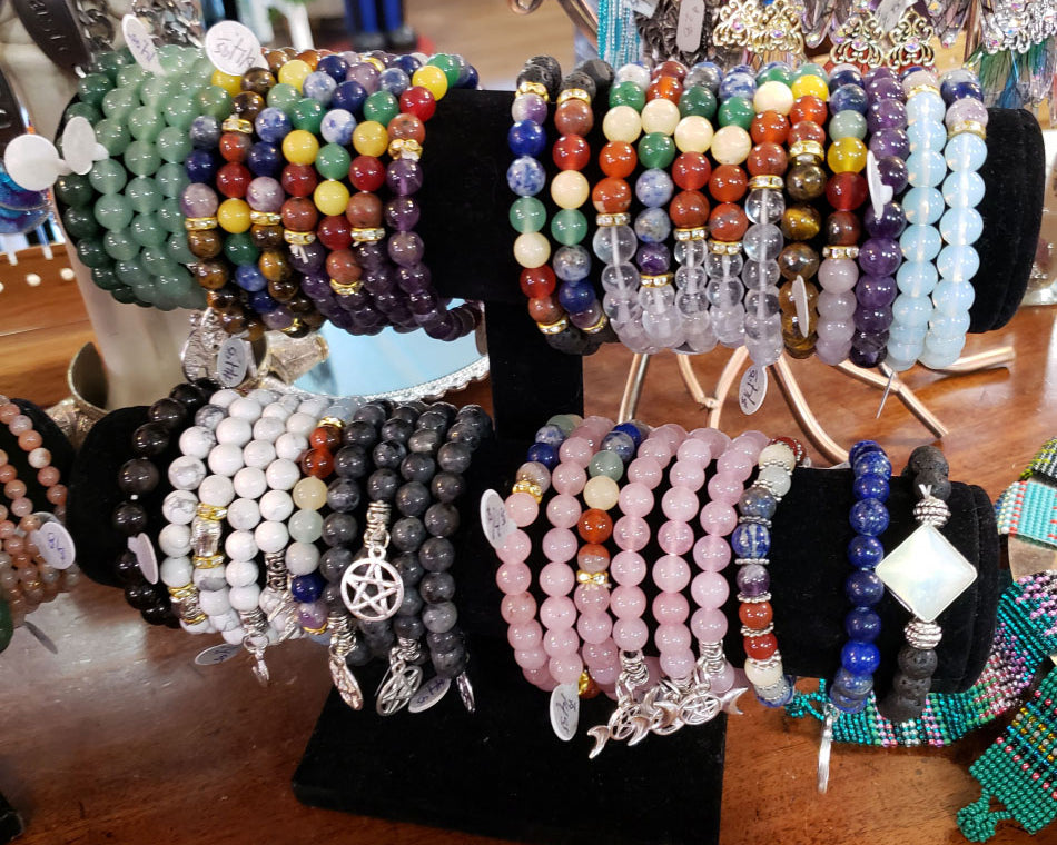 Crystal bracelets for chakra cleansing on a black velvet jewelry stand.