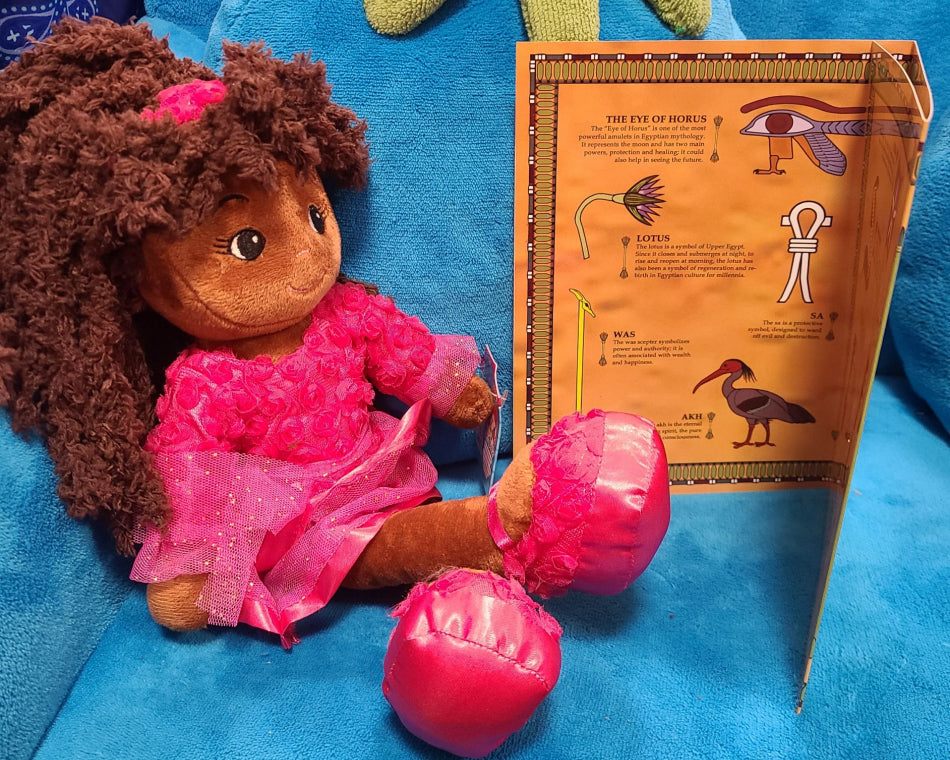 The picture showcases one of our charming dolls engrossed in a booklet about Egypt.