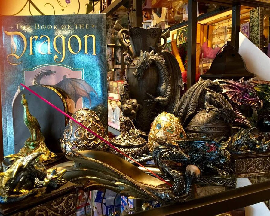 Decorative display with 'The Book of the Dragon' and dragon figurines, including dragon eggs and incense holders.