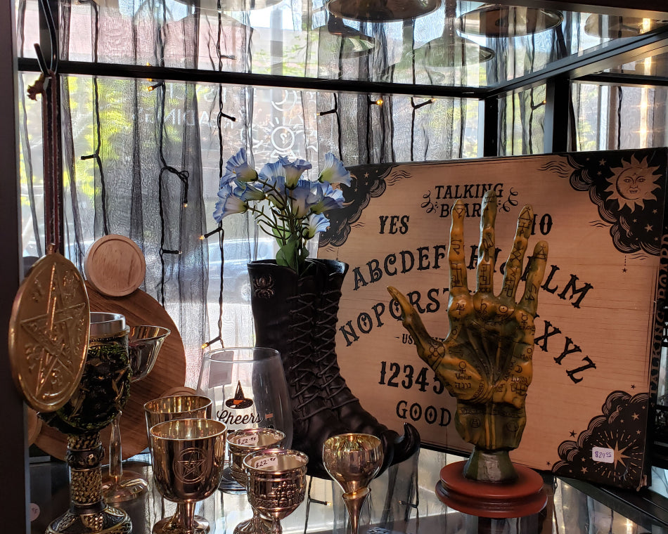 Cups and Goblets on a shelf in the shop. There is a spirit board in the background.
