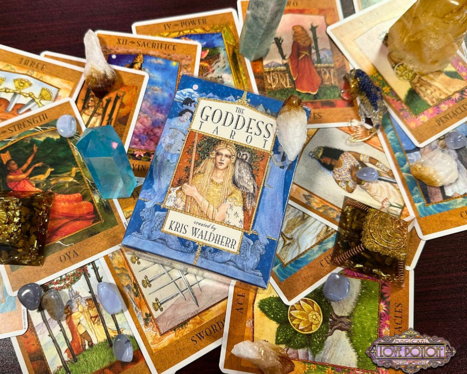 The Goddess Tarot divination card deck by Kris Waldherr surrounded by sample cards and crystals.