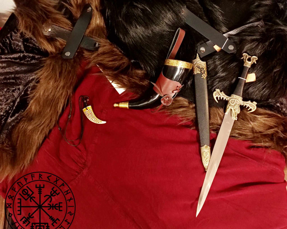 A red dress complemented by a faux fur-collared cloak accessorized with a drinking horn, a dagger, and a tooth necklace.