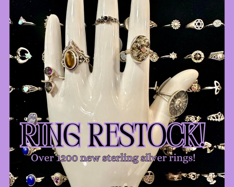 A palm reading hand wearing our rings with a drawer of more rings in the background.