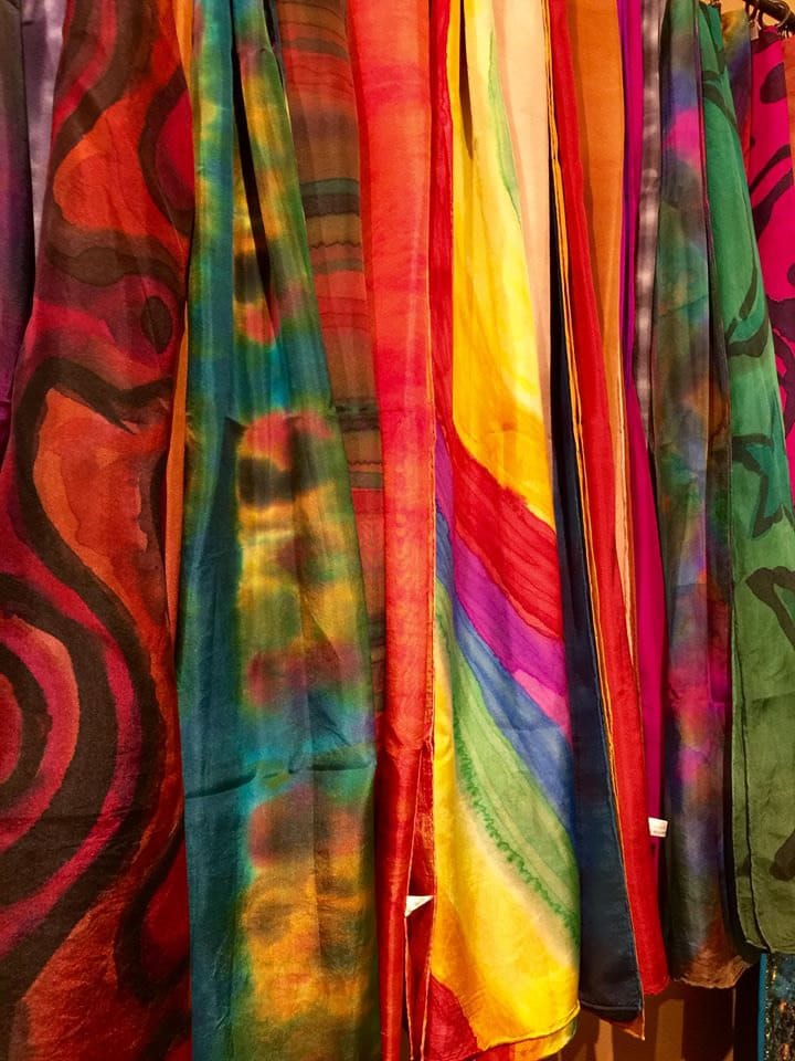 Colorful tie-dye fabrics hanging on a rack.