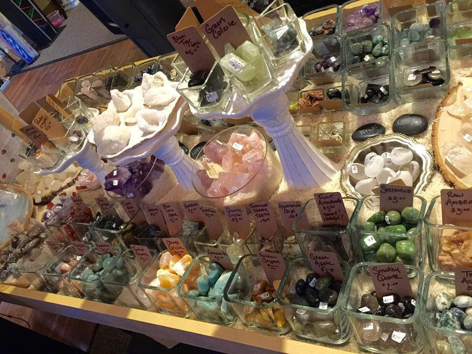 Display of various crystals and stones in glass containers with price tags.