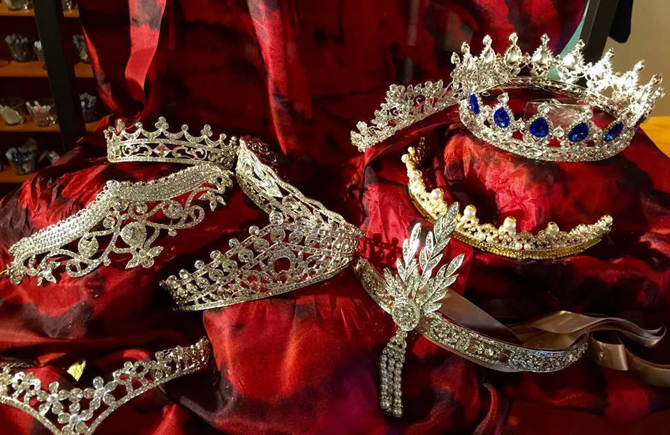 Set of decorative jeweled tiaras on a red fabric background.