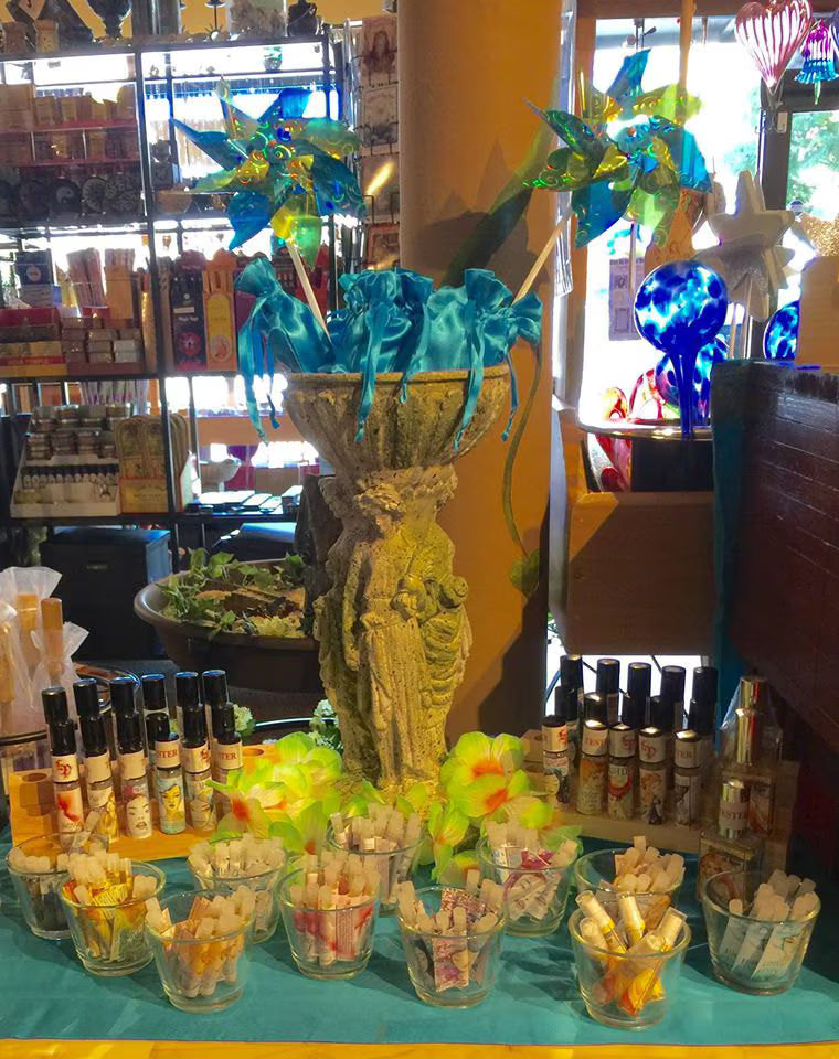 Summer perfume display with tester roller bottles, trial vials, Hawaiian flowers, pinwheels, and bright blue travel pouches.
