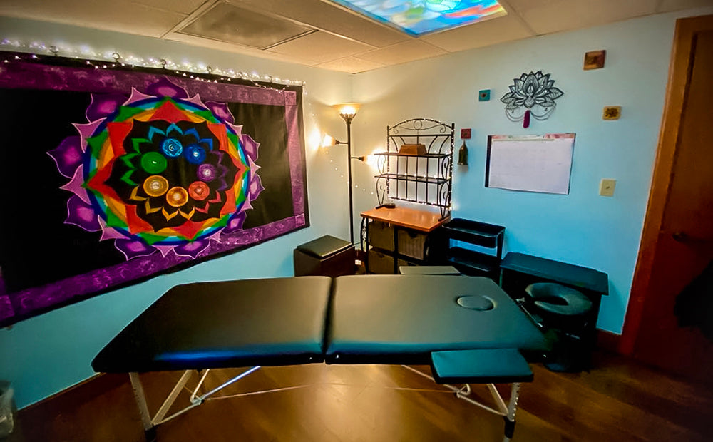 The massage table and display shelf areas in our Room of Requirement, with fairy lights and a chakra tapestry on the wall.