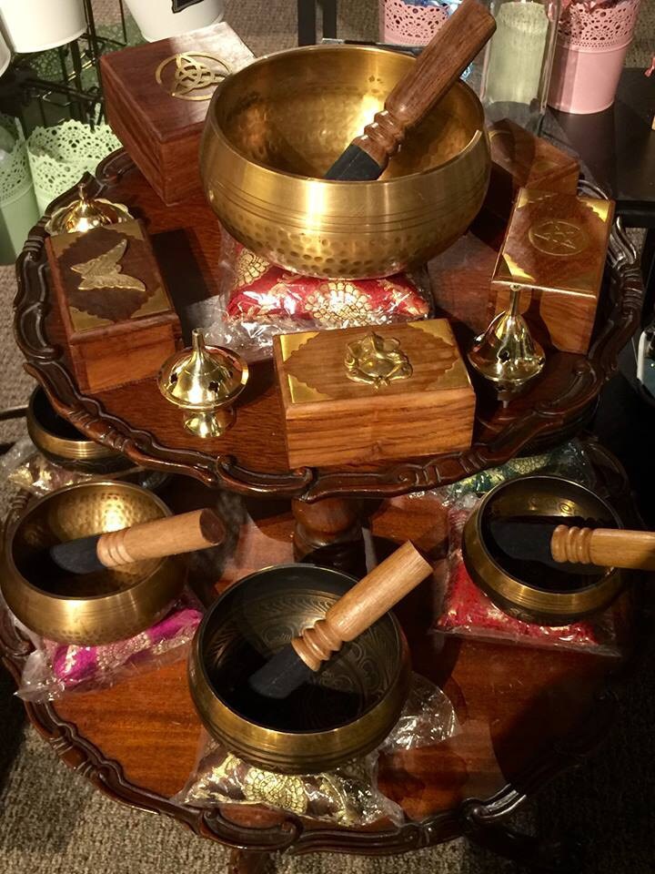 Set of Tibetan singing bowls on a wooden stand with various accessories.