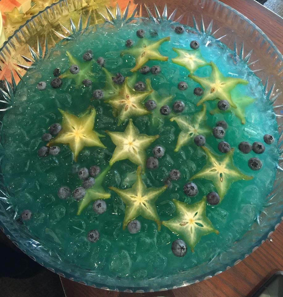 Punch bowl filled with star fruit slices and blueberries in a blue fruit punch for one of our shop parties.