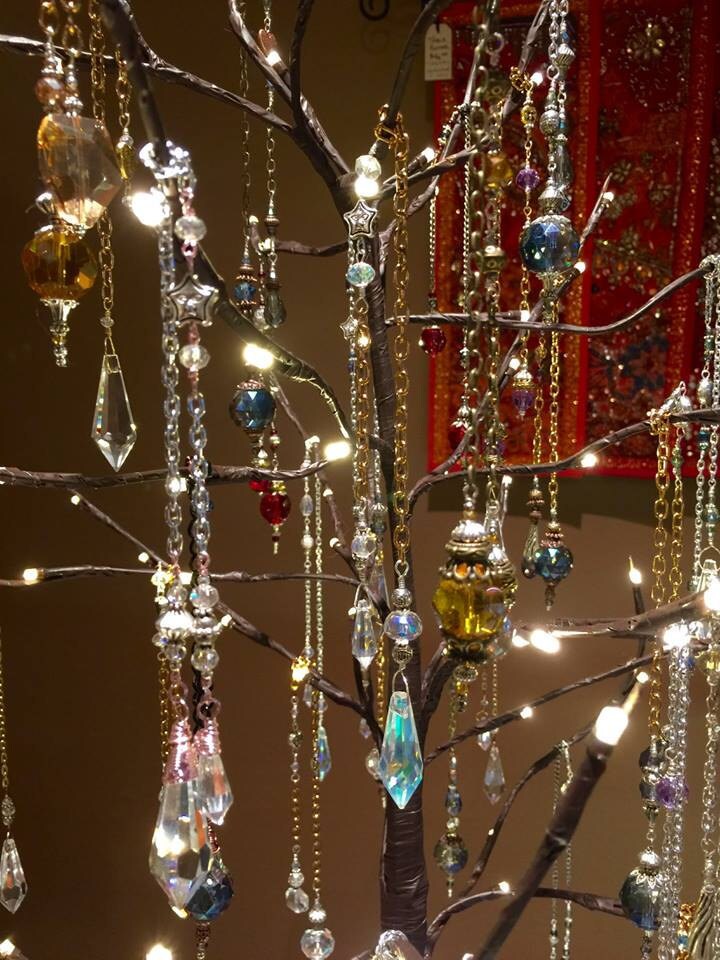 Crystal pendant ornaments and sun catchers hanging on the limbs of an artificial tree with fairy lights.