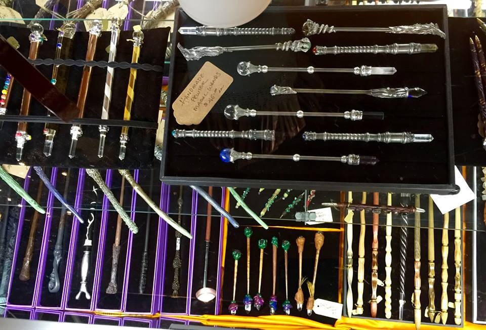 Collection of decorative wood, resin, metal, and crystal wands in a display case at our store.