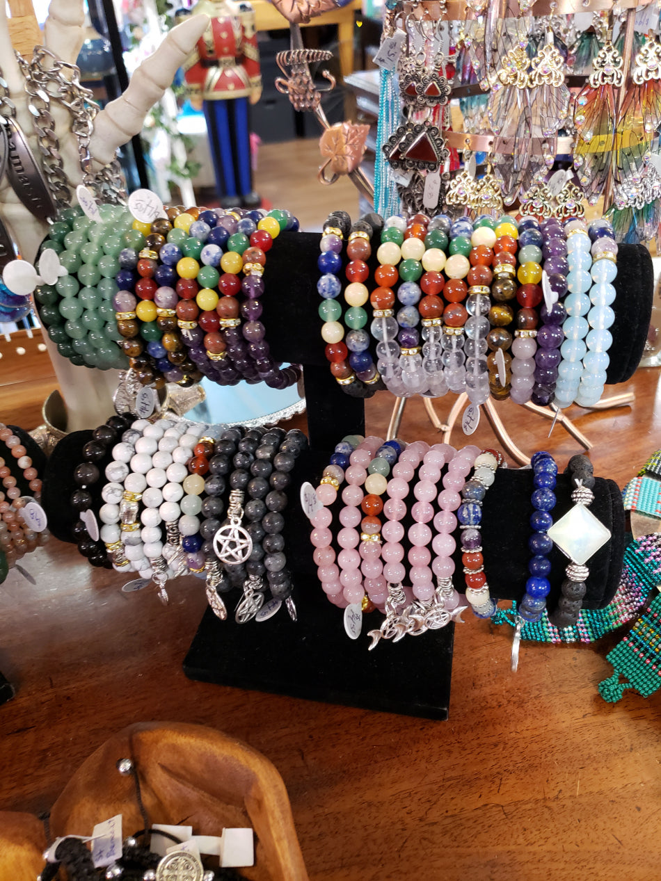 Crystal bracelets for chakra cleansing on a black velvet jewelry stand.