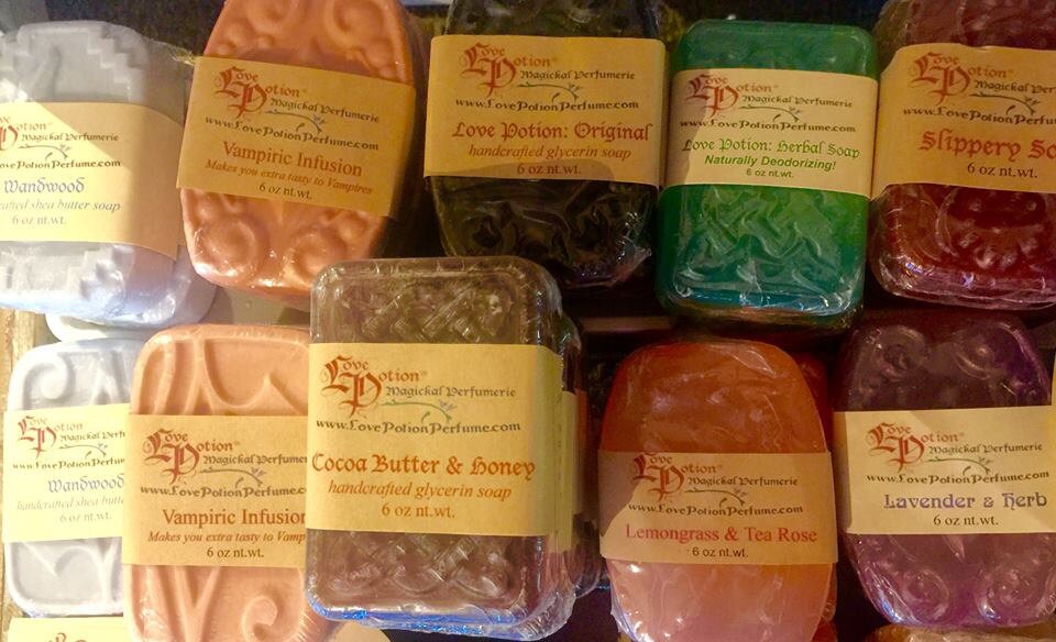 Assorted handcrafted Love Potion scented glycerin soaps with visible labels on a white background.