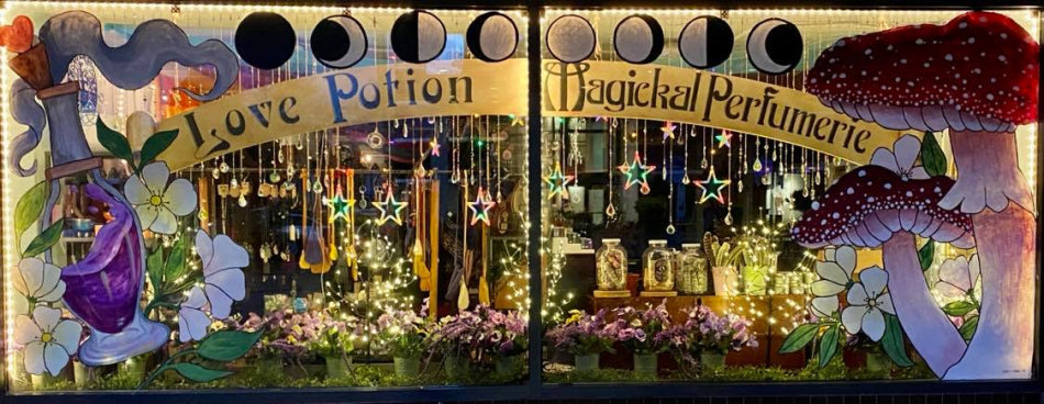Magical Perfumerie window display with potion bottles, flowers, moon phases, and giant mushrooms.