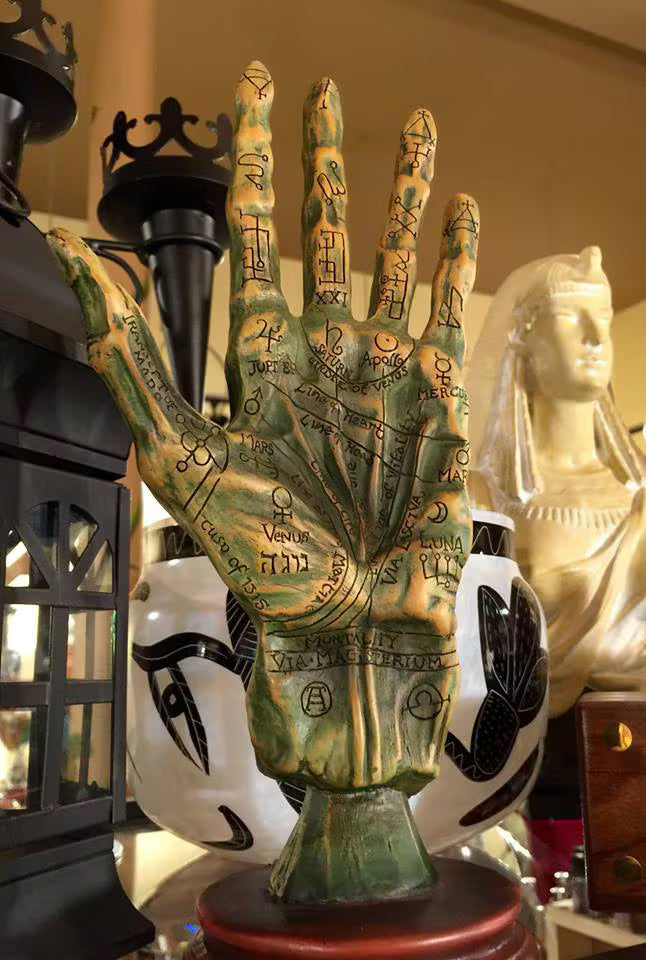 Decorative hand sculpture covered in astrological and other symbols as a palm reading guide.