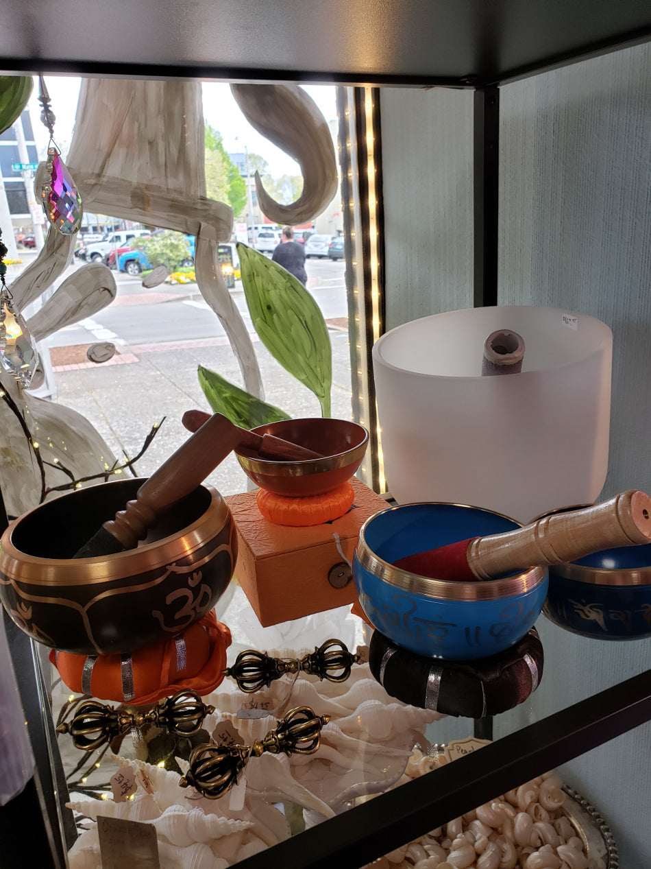 This image is of a few different singing bowls on display in front of an open window.