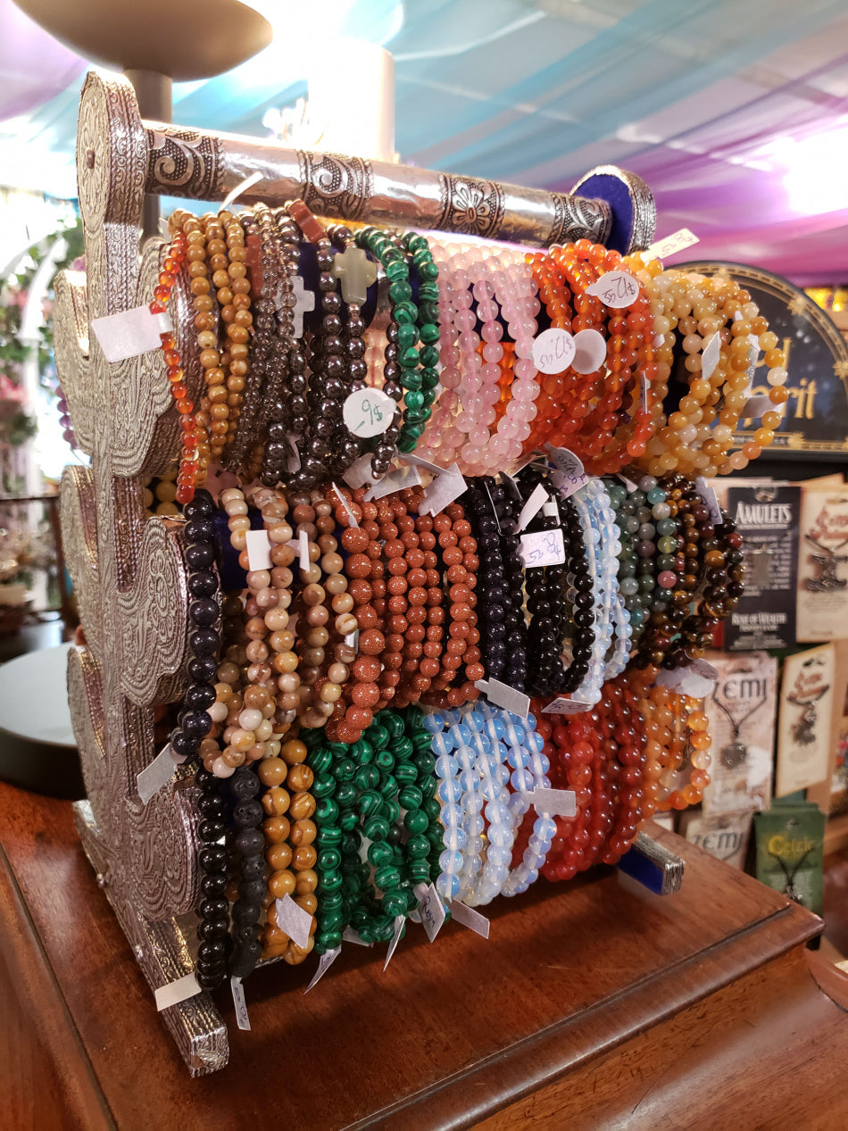 A range of crystal bead bracelets on a holder in the jewelry section.